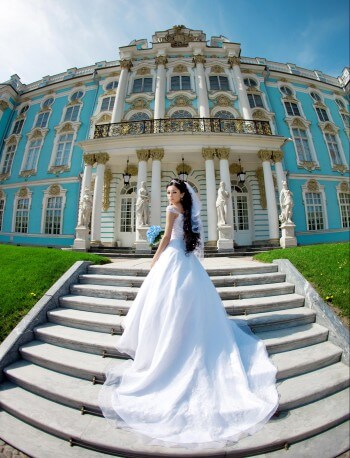 Im Brautkleid vor einem Schloss